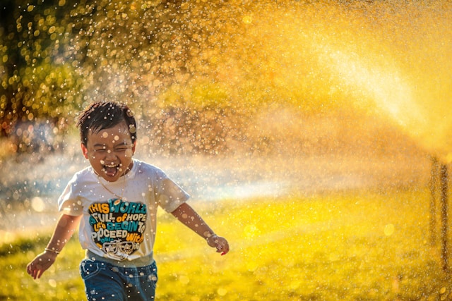 Einen Kind die im Sommer mit Wasser spielt.