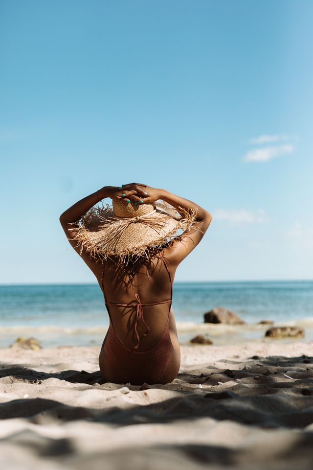 pexels-karola-g-8362262 Eine Frau, die im Schatten am Strand sitzt.